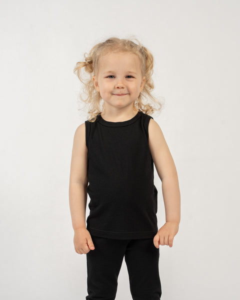 Young child wearing a black sleeveless top and black pants on a white background