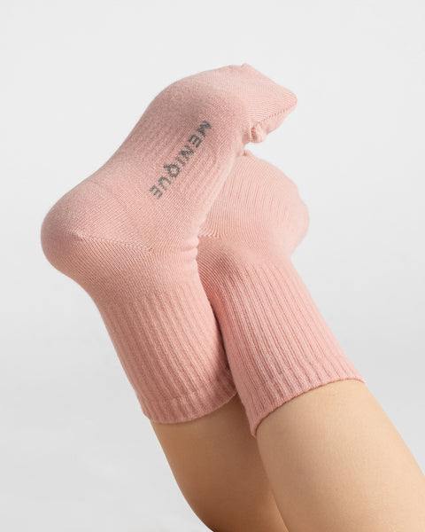 Close-up of raised feet wearing dusty rose ribbed knit socks showing branding detail on the bottom sole.