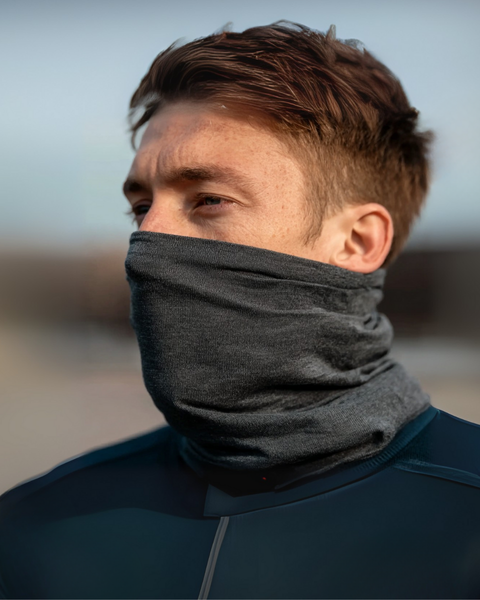 Man in sportswear with a dark gray Merino wool long neck gaiter covering his face, outdoors in natural light.