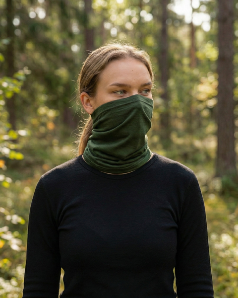 Woman in dark green merino wool long neck gaiter standing in forest, temperature-regulating windproof face cover for hiking and trekking