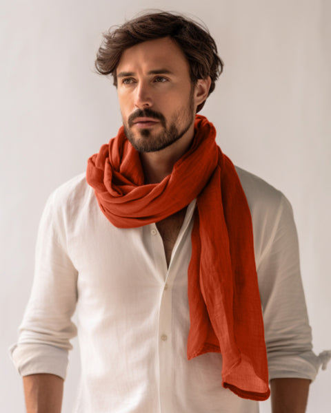 Man wearing a white shirt and orange scarf against a plain background