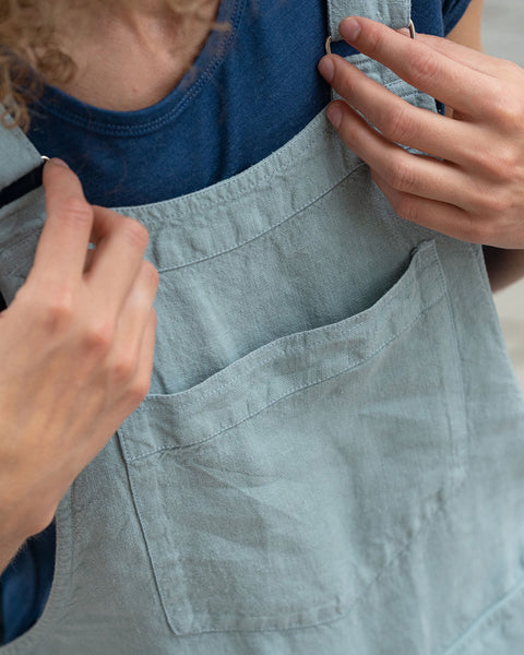 Close-up of a woman holding her linen jumpsuit in her hands.