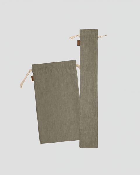 A studio laydown of two olive green linen bread bags against a plain light gray background. The set includes one medium rectangular bag and one long, slender baguette bag, both featuring natural rope drawstrings and small brown brand tags.