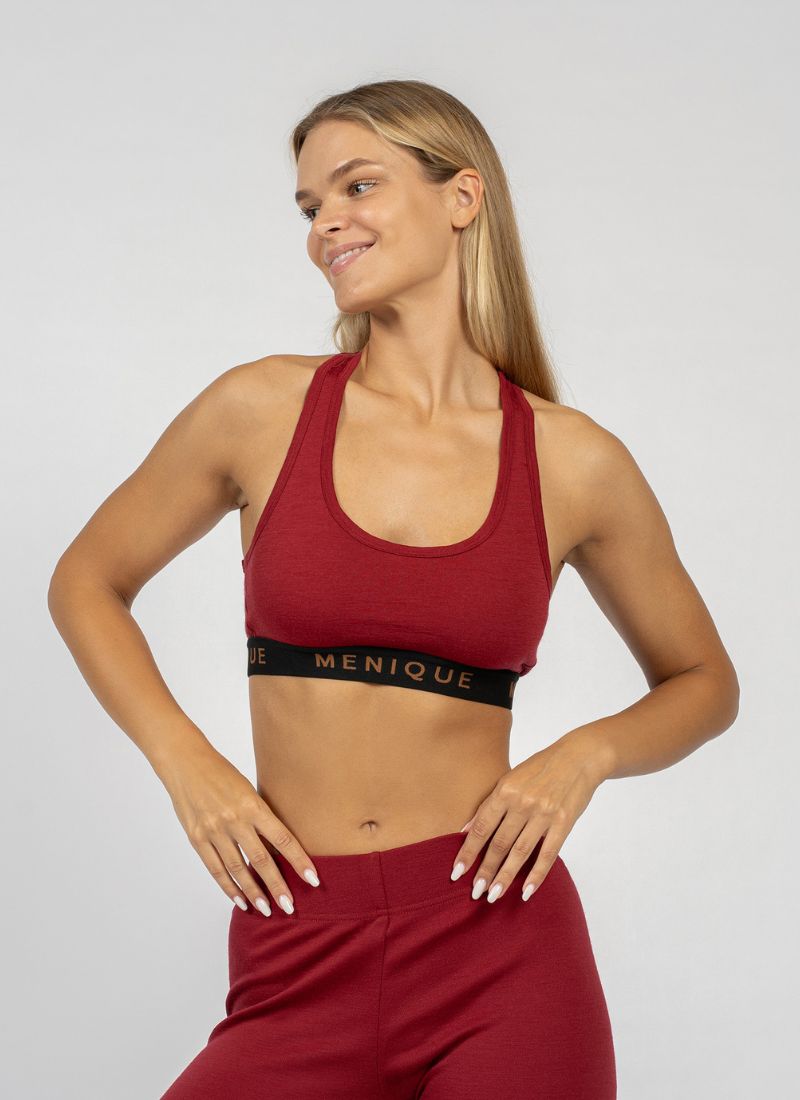 Woman wearing a red sports bra and leggings with 'Menique' branding on a light gray background