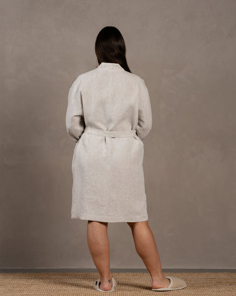 The menique women's linen bathrobe in natural color. The woman is showing the back of the bathrobe in size L-XL
