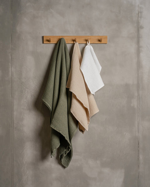 all size waffle towels in different colors hanging on a wooden rack.