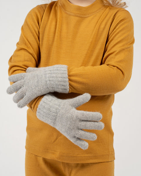 Child wearing a spicy yellow long-sleeve shirt and light gray gloves on a white background