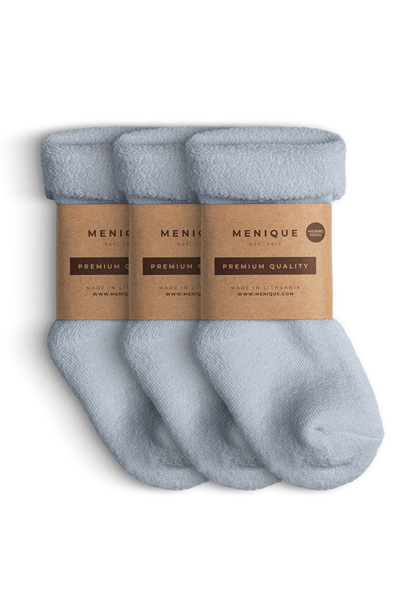A 3-pack of kids’ light blue sherpa-lined merino wool socks with Menique branding.