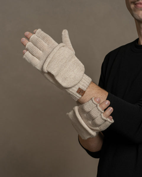 Hands wearing creamy beige merino convertible gloves, demonstrating fingerless use and foldable mitten top for versatility.