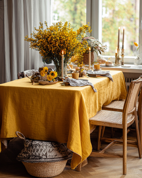 Vibrant yellow linen tablecloth with floral centerpiece for a warm, inviting dining room setup.