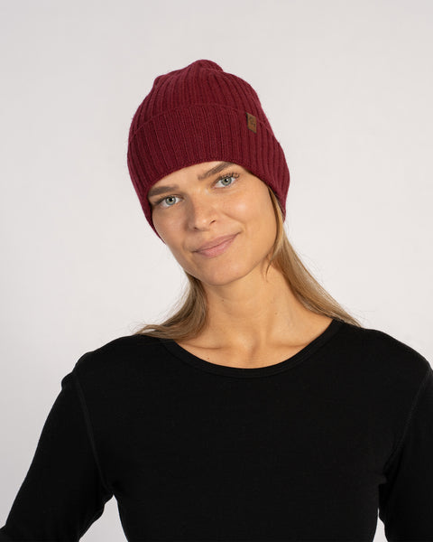 Unisex ribbed beanie in royal cherry red, knitted from Merino wool and cashmere, shown front view on a model with black top.