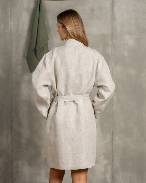 The menique women's linen bathrobe in natural color. The woman is showing the back of the bathrobe.