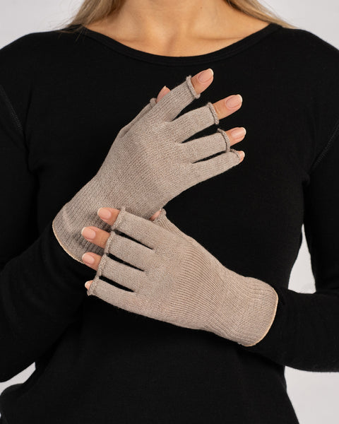 Close-up of a woman’s hands wearing creamy-beige fingerless merino gloves, palms facing inward and fingers visible.