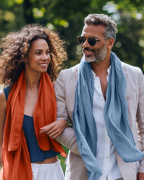 Man and woman walking together in a park, both wearing scarves.